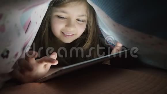 晚上小女孩用数码平板电脑盖着视频的预览图