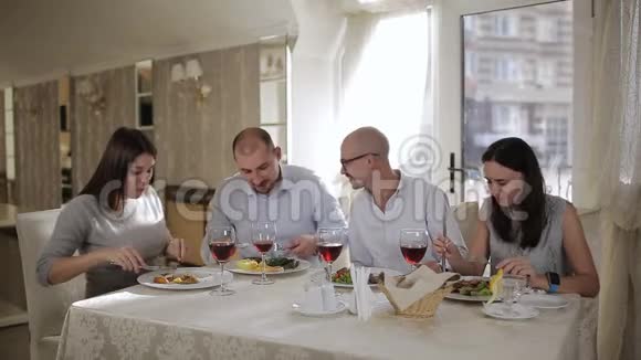 四个朋友在餐厅吃肉喝红酒在杯子里视频的预览图