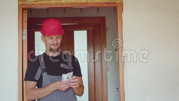 一个戴头盔的建筑工人在修理过的公寓里数钱视频的预览图