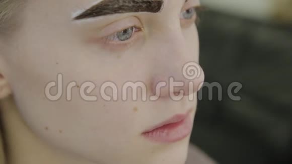 美丽的年轻女孩在美容院等待眉毛油漆被吸收视频的预览图