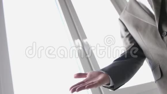 房地产经纪人在窗口背景上把钥匙交给客户然后他们握手慢动作视频的预览图