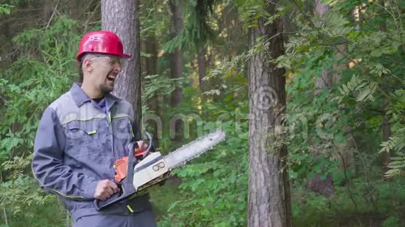 在森林里戴着电锯的头盔笑工人的画像视频的预览图