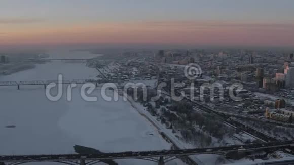 冬天是一条冰冻的大河日落时两岸都是白雪覆盖的大城市视频的预览图