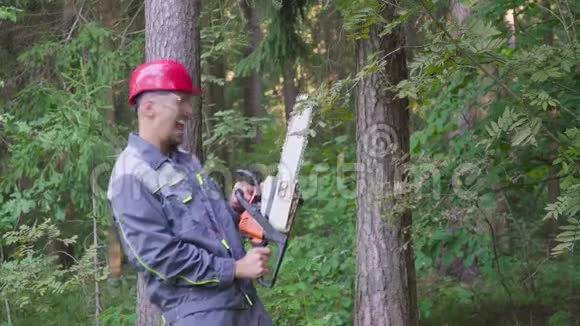 在森林里戴着电锯的头盔笑工人的画像视频的预览图