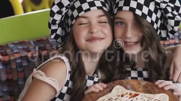 两个带着微笑的年轻女孩为照相机赠送一个披萨视频的预览图