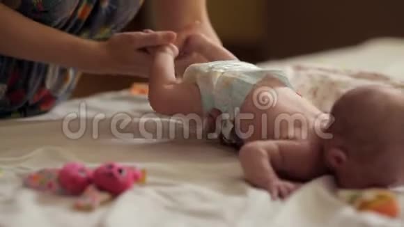 两个孩子躺在床上一个睡觉另一个妈妈为新生儿做特殊的体操视频的预览图