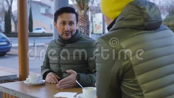 晚上两名穿暖气泡夹克的男运动员在咖啡馆的室外训练后交谈一个男人视频的预览图
