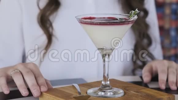 在咖啡馆的桌子上放着微笑旋转鸡尾酒果冻的快乐女孩视频的预览图
