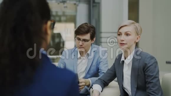 在现代办公中心女商人与坐在沙发上的商业伙伴交谈并为未来的交易感到困惑视频的预览图
