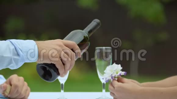 男人在酒杯里斟红酒女士捧花浪漫的约会恋情视频的预览图