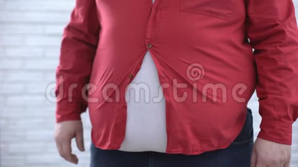 身材魁梧的男人试图扣上红色衬衫外表不安全健康视频的预览图