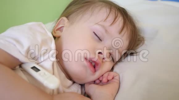 幼儿睡在医院病房的白色被褥上用温度计测量体温对儿童的治疗视频的预览图