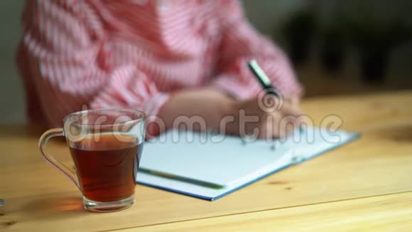一个女孩在工作时喝茶坐在桌子旁一个透明的茶杯视频的预览图