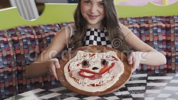 那个年轻女孩在镜头前微笑着展示一个比萨饼慢慢地视频的预览图