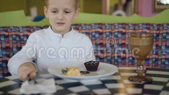 英俊的微笑男孩开始在咖啡馆里吃美味的甜点4K视频的预览图