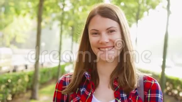 幸福快乐的年轻女人享受大自然的肖像漫步在绿色公园微笑着面对镜头视频的预览图