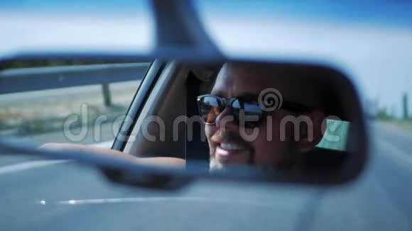 戴太阳镜的年轻人正在开车车辆后视镜内的反射面视频的预览图