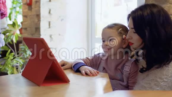 妈妈和小女儿在咖啡馆里看动画片等待他们的点菜视频的预览图