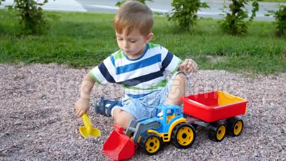 4k视频小男孩在操场上玩耍玩具拖车里装砾石视频的预览图