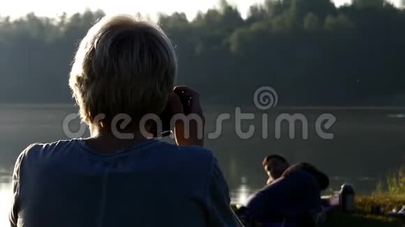 一个金发男人在夏天的湖岸拍一张躺着的照片视频的预览图
