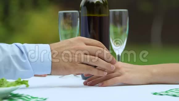 可爱的丈夫温柔地牵着妻子的手用一瓶酒放松浪漫视频的预览图