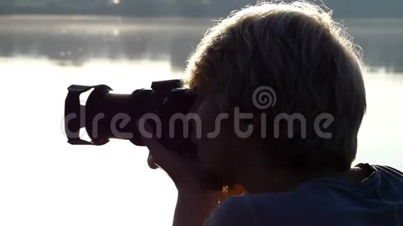 在夏日灿烂的夕阳下金发男子向森林湖射击视频的预览图