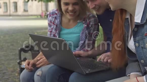 学生们看着长凳上的笔记本电脑视频的预览图