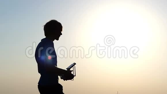 青少年在太阳落山时使用面板操作四翼飞行器视频的预览图