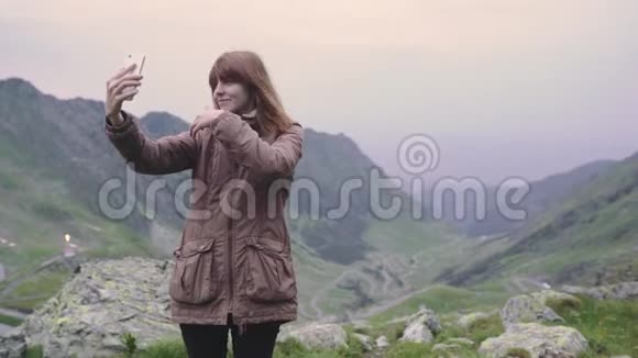 一个年轻的女人徒步旅行者爬上山脉在智能手机相机上自拍罗马尼亚喀尔巴阡山脉视频的预览图