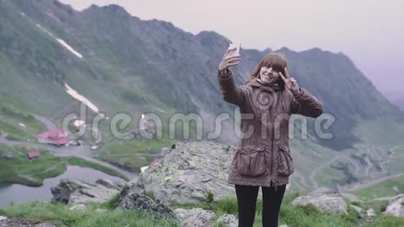 一个年轻的女人徒步旅行者爬上山脉在智能手机相机上自拍罗马尼亚喀尔巴阡山脉视频的预览图