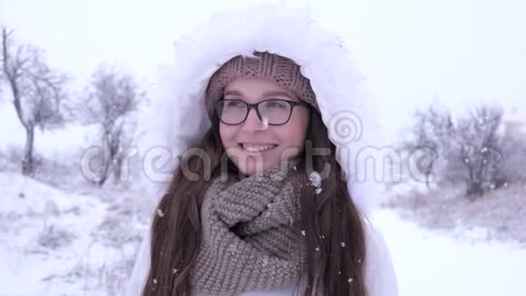冬天戴眼镜的微笑女孩站在降雪下视频的预览图