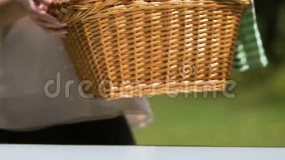 女性将野餐篮放在餐桌上为家庭周末提供露天餐视频的预览图