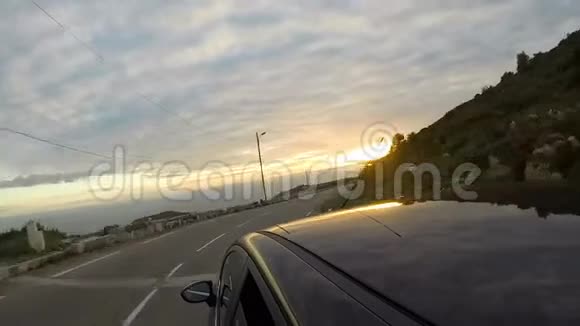 汽车沿着高速公路快速行驶朝日落方向行驶海岸线位于山脚下视频的预览图
