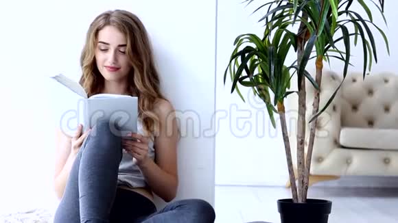 快乐的年轻女子在家放松和看书视频的预览图