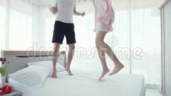 可爱的亚洲夫妇在卧室里跳上床视频的预览图