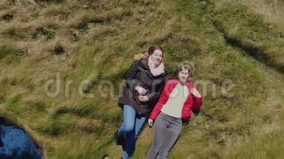 两个女孩躺在爱尔兰海岸悬崖的草地上从上面看到无人驾驶飞机视频的预览图