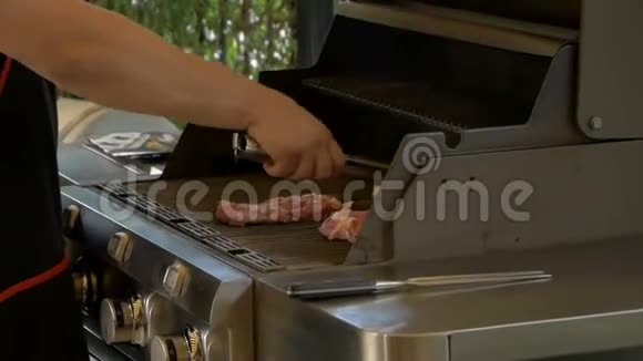 专业厨师使用金属钳子来翻转在煤气烤架上煮熟的肉牛排露天烹饪食物视频的预览图