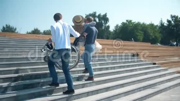两个男人把一个坐轮椅的女人抬到台阶上视频的预览图
