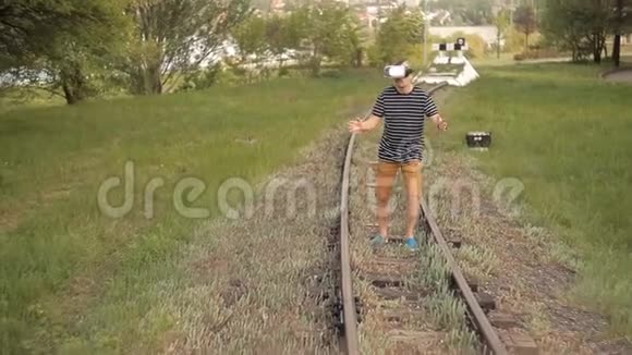 一个年轻人戴着虚拟现实头盔在铁路运输轨道上查看图片视频游戏虚拟世界视频的预览图
