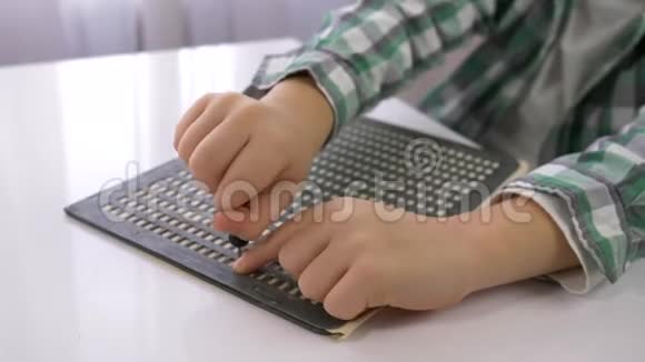 视力受损的男孩学习书写字体盲文坐在明亮的房间里的桌子上双手视频的预览图
