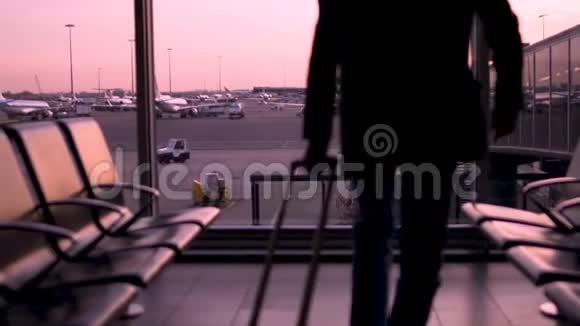 坐在等候大厅里的人剪影紫色的日落和背景上的飞机视频的预览图