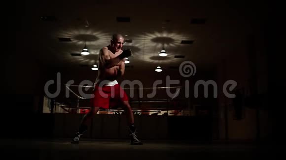 职业拳击手在拳击手套的拳击场背景下与影子举行战斗视频的预览图