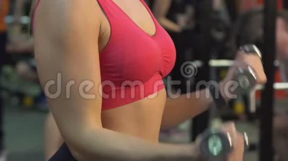 运动女性在健身房举起哑铃锻炼健身慢动作视频的预览图