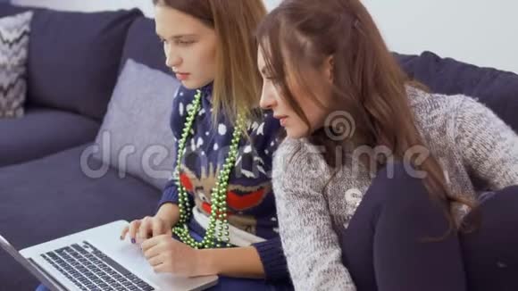 两个穿毛衣的漂亮女孩在家里在网上购物视频的预览图
