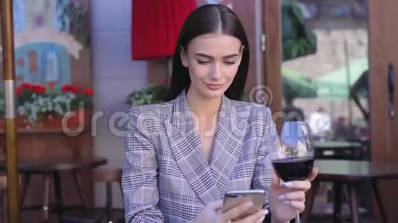 微笑的女人喝酒在餐馆用电话视频的预览图