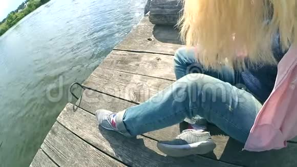 穿着蓝色牛仔裤的金发女孩坐在一个古老的木墩边上视频的预览图