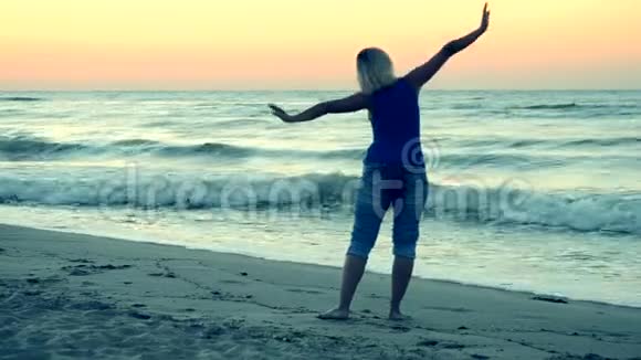 女孩站在海边伸展模仿飞翔视频的预览图