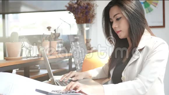 4K镜头忙碌的商务女性早上在城里的咖啡店里用笔记本电脑和计算器工作布辛视频的预览图