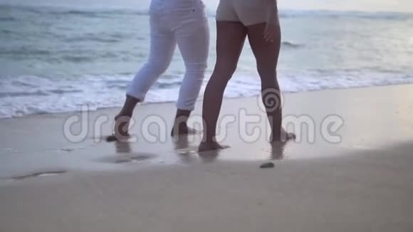 两人手牵手在沙滩上慢动作女孩和男孩腿低镜头视频的预览图