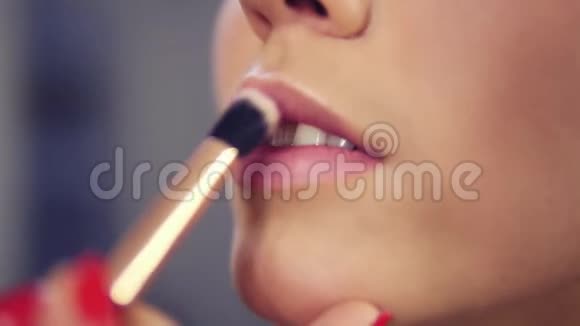 专业化妆师在美容时尚行业模特嘴唇上涂口红底漆近景视频的预览图